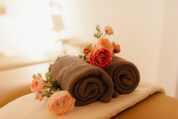 Massageliege dekoriert mit gerollten Tüchern und Blumen